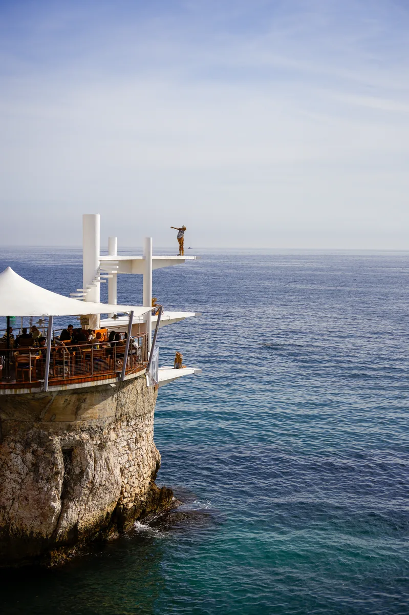 A figure on a diving platform above the sea
